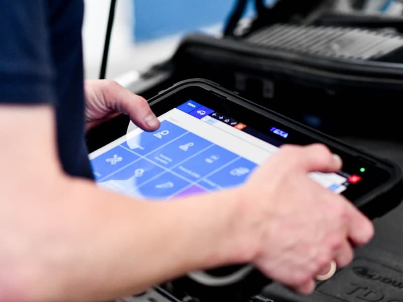 Valise de diagnostic branchée sur la prise OBD sous le tableau de bord d’un véhicule